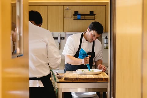 A chef plating canapés in the galley during service.