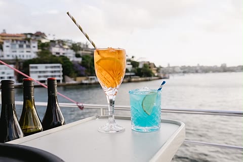 Cocktails set out on a table by the water at sunset.