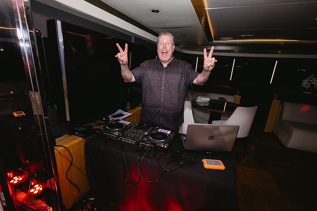 A DJ performing with warm red uplighting at an evening Christmas function.