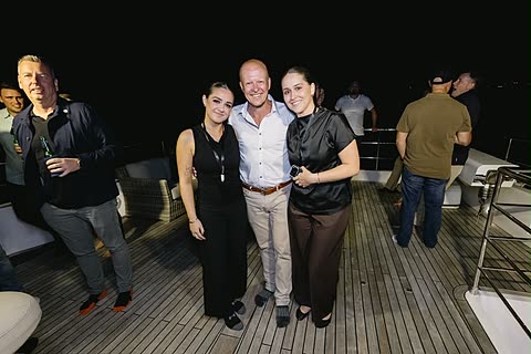 Three guests photographed together on deck in the evening.
