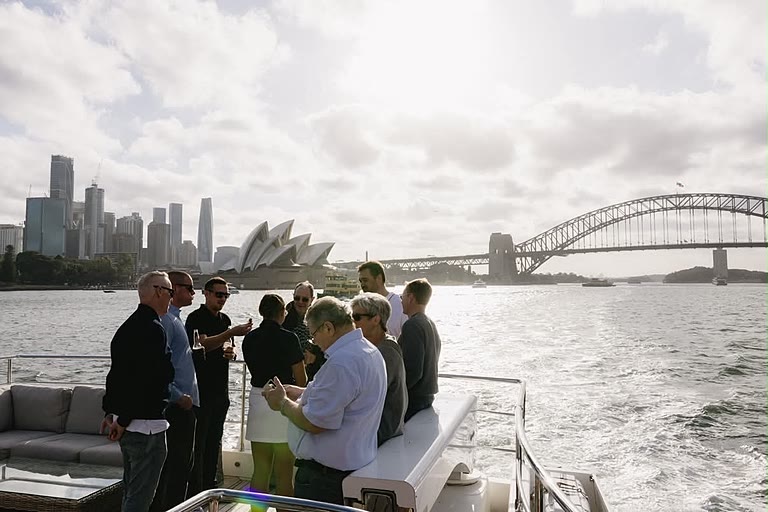 Guests gathered on deck with the Sydney Opera House and Harbour Bridge behind them.