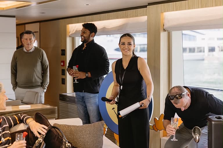 The event manager with a microphone and run sheet, welcoming guests aboard.