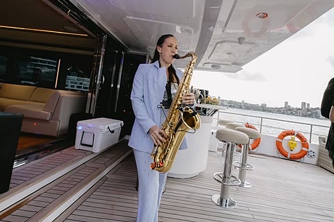 A live saxophonist performing on the aft deck during golden hour.